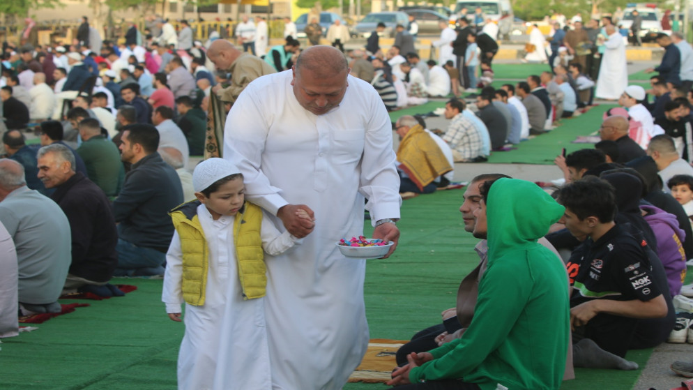 شخص وابنه يوزعان الحلوى في صلاة العيد. (صلاح ملكاوي/ المملكة))