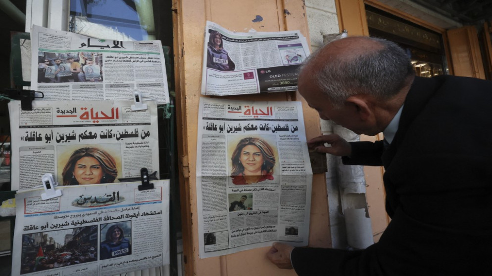 فلسطيني في الخليل يلقي نظرة على الصفحات الأولى من الصحف المحلية التي تتحدث عن استشهاد شيرين أبو عاقلة، 12 أيار/مايو 2022. (أ ف ب)