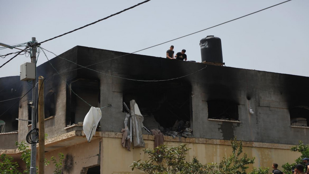 فلسطينيون يتفقدون بناية سكنية في مخيم جنين قصفتها قوات الاحتلال الإسرائيلي بالقذائف. 13/05/2022. (عدي دعيبس/ وفا)