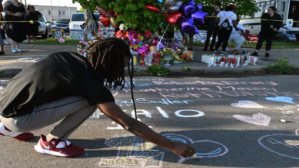 أشخاص يكتبون رسائل أمام نصب تذكاري بالقرب من متجر  بوفالو، بعد مقتل 10 أشخاص. (أ ف ب)