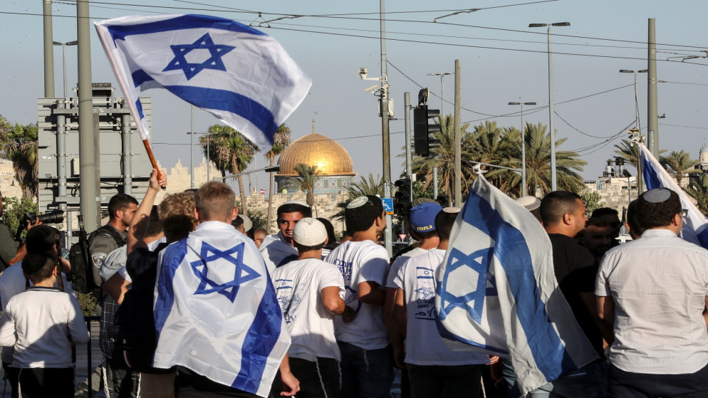 إسرائيليون يسيرون بالأعلام خارج البلدة القديمة في القدس المحتلة. 15 حزيران/يونيو 2021. (رويترز)