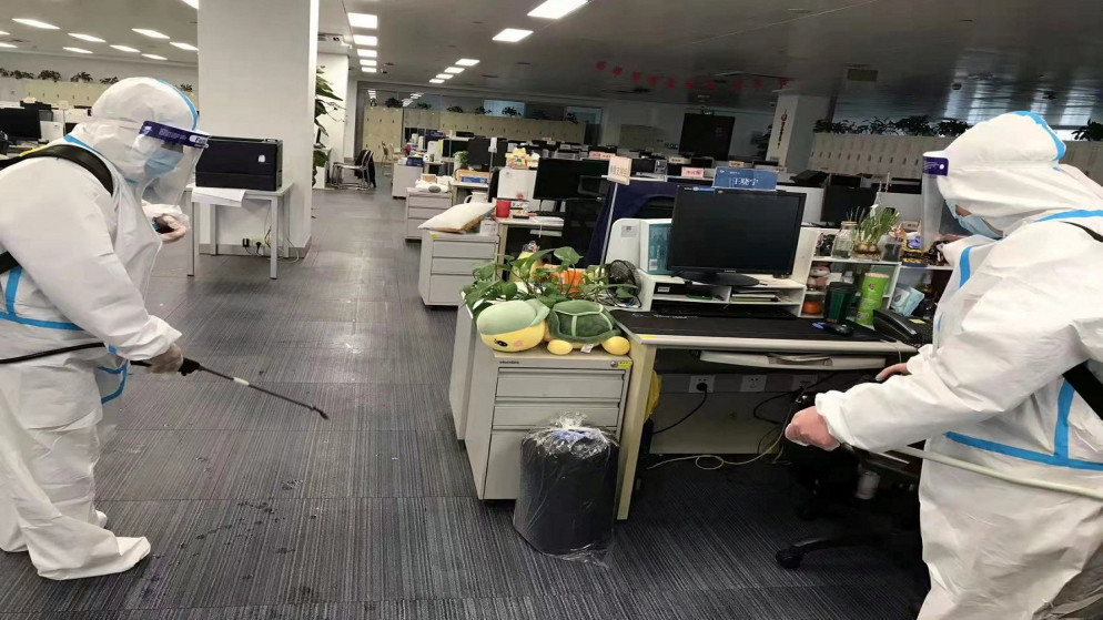 عمال يرتدون بدلات واقية يقومون بتطهير مكتب في بنك خلال فترة الإغلاق لكبح جماح انتشار مرض فيروس كورونا في مدينة لوجياتسوي في شنغهاي الحي المالي، الصين. 8 أبريل/ نيسان ، 2022. (رويترز)