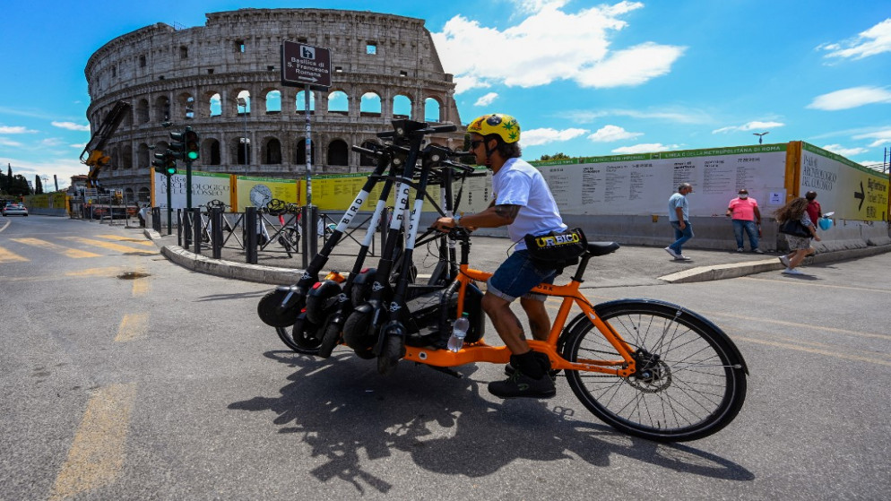 موظف ينقل الدراجات البخارية الكهربائية المشتركة بالقرب من الكولوسيوم في روما. (أ ف ب)