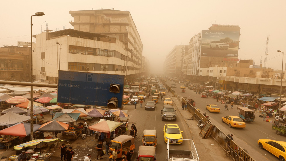 السيارات تتجول والسكان يتجمعون في سوق الشورجة بالجملة خلال عاصفة رملية في بغداد. (رويترز)