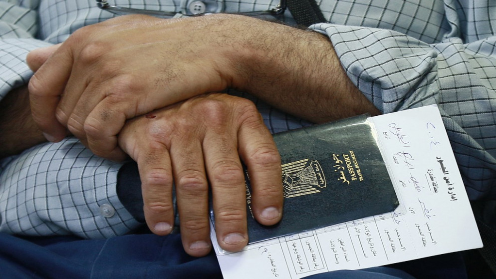 مسافر يحمل جواز سفره الفلسطيني في غرفة انتظار في جسر الملك حسين، 19 تموز/يوليو 2022. (أ ف ب)