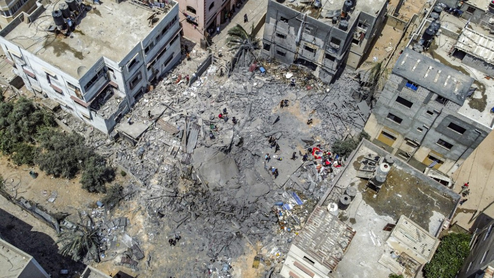 فلسطينيون يتفقدون أنقاض مبنى منهار دمرته غارة من طائرة تابعة للاحتلال الإسرائيلي في مدينة غزة، 6 آب/أغسطس 2022 (أ ف ب)