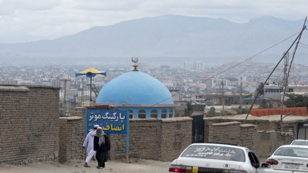 رجال أفغان يمرون بالقرب من القبة الزرقاء لمسجد بعد يوم من الانفجار في ضواحي كابل .18 أغسطس 2022. (أ ف ب)