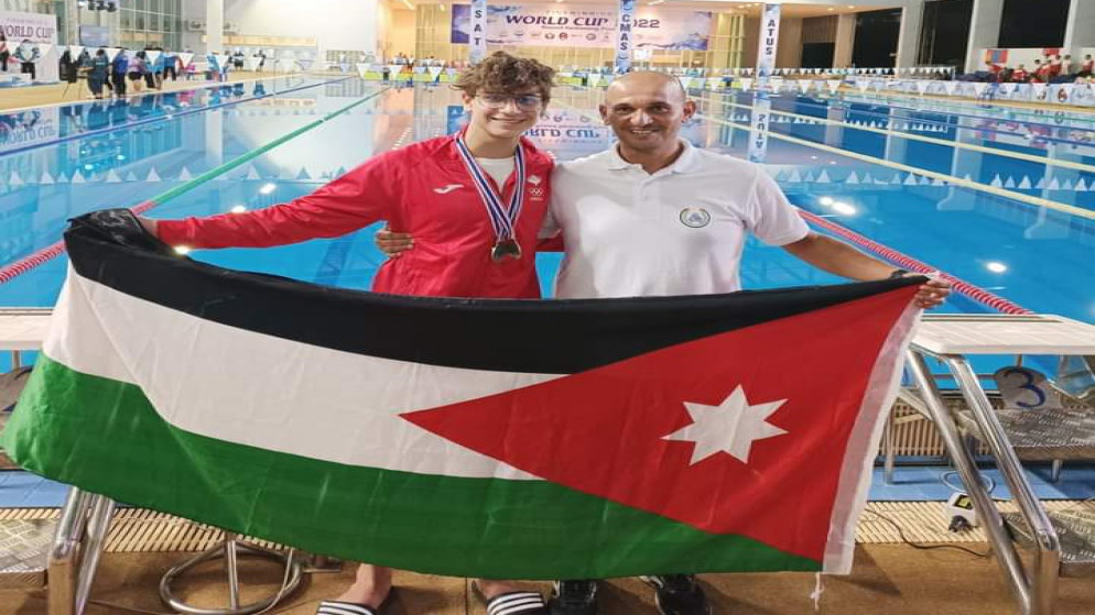 لاعب المنتخب الوطني لسباحة الزعانف سري الحرازنة (يسار) يحتفل برفع علم الأردن في بطولة كأس العالم. (اللجنة الأولمبية الأردنية)