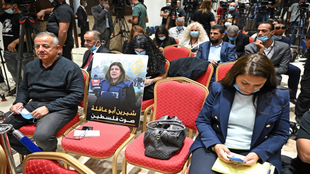 صحفيون خلال مؤتمر صحفي يضعون صورة الصحفية شيرين أبو عاقلة. (أ ف ب)