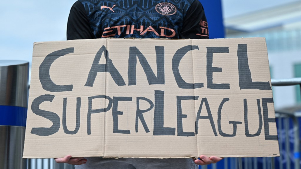 مشجع يحمل لافتة تنتقد فكرة إقامة دوري السوبر الأوروبي الجديد ويدعو لإلغائه، خارج ملعب ستامفورد بريدج في لندن، 20 نيسان/أبريل 2021. (أ ف ب)