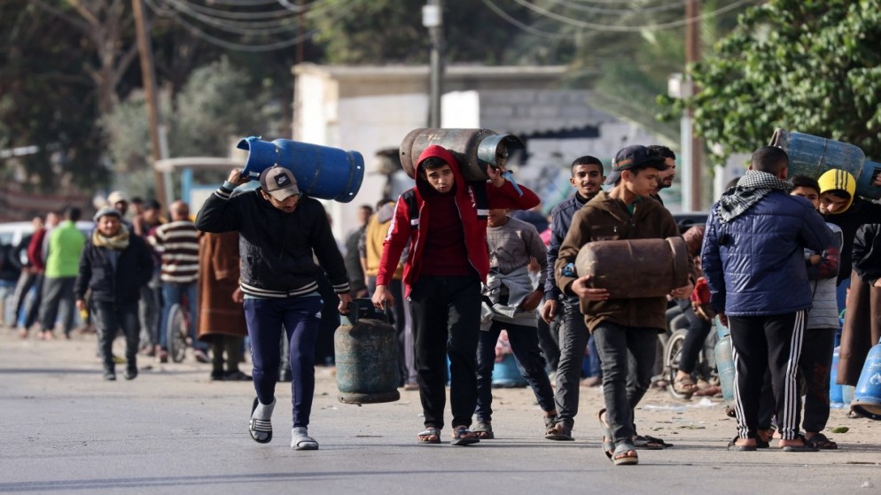 أشخاص يحملون عبوات غاز فارغة ليتم ملؤها بغاز الطهي من خزان دخل إلى القطاع الفلسطيني عبر معبر رفح مع مصر.25 نوفمبر، 2023..(أ ف ب)