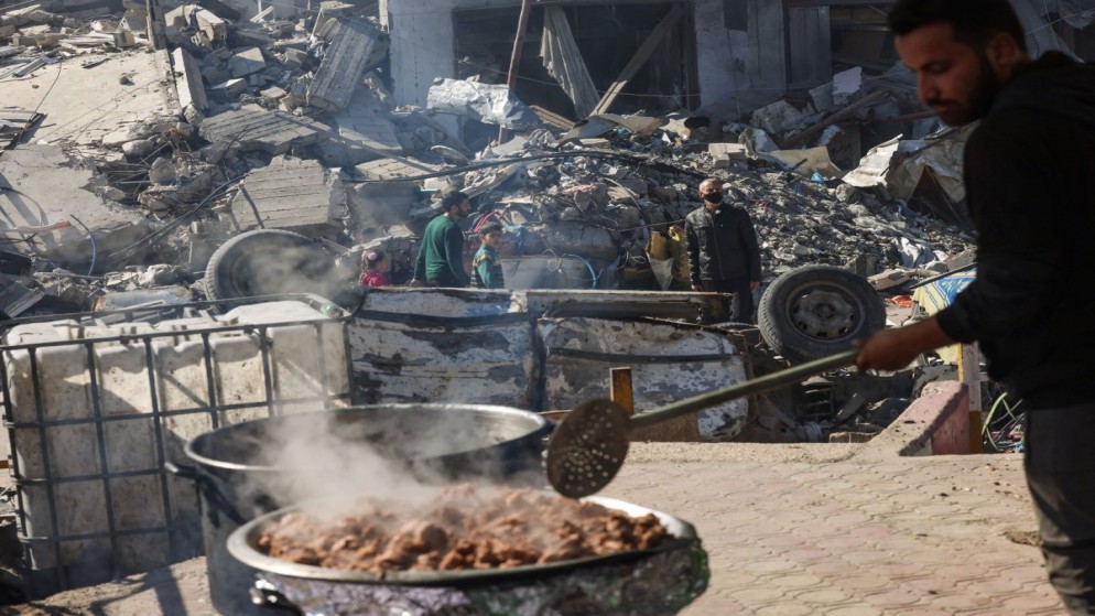 رجل فلسطيني يطهو بالقرب من أنقاض المباني التي دمرتها غارات الجيش الإسرائيلي في نقطة التبرعات الغذائية التي قدمتها مجموعة خيرية في مدينة رفح بجنوب قطاع غزة. 30 نوفمبر 2023. ( ا ف  ب)
