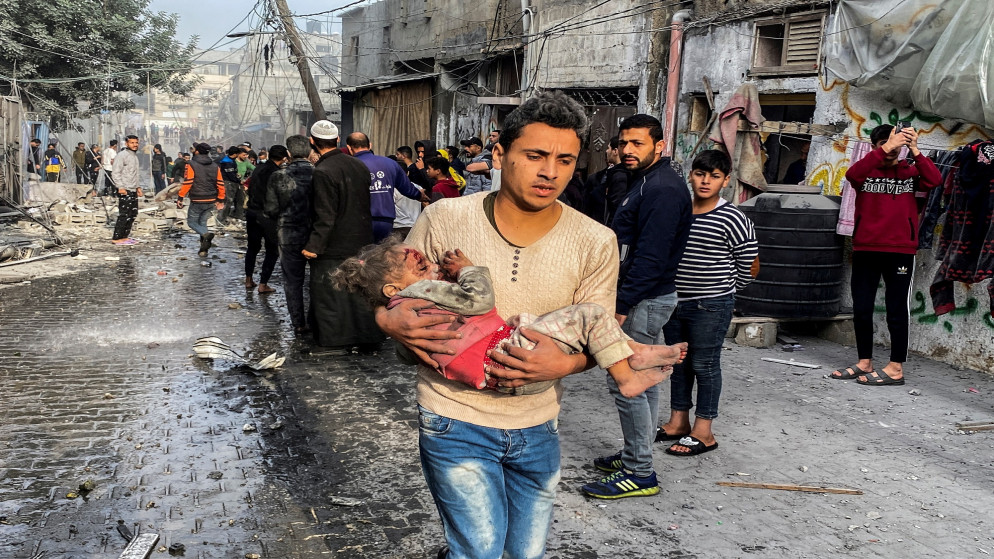 فلسطيني يحمل طفلا أصيب خلال العدوان الإسرائيلي على قطاع غزة.2/12/2023.(أ ف ب)