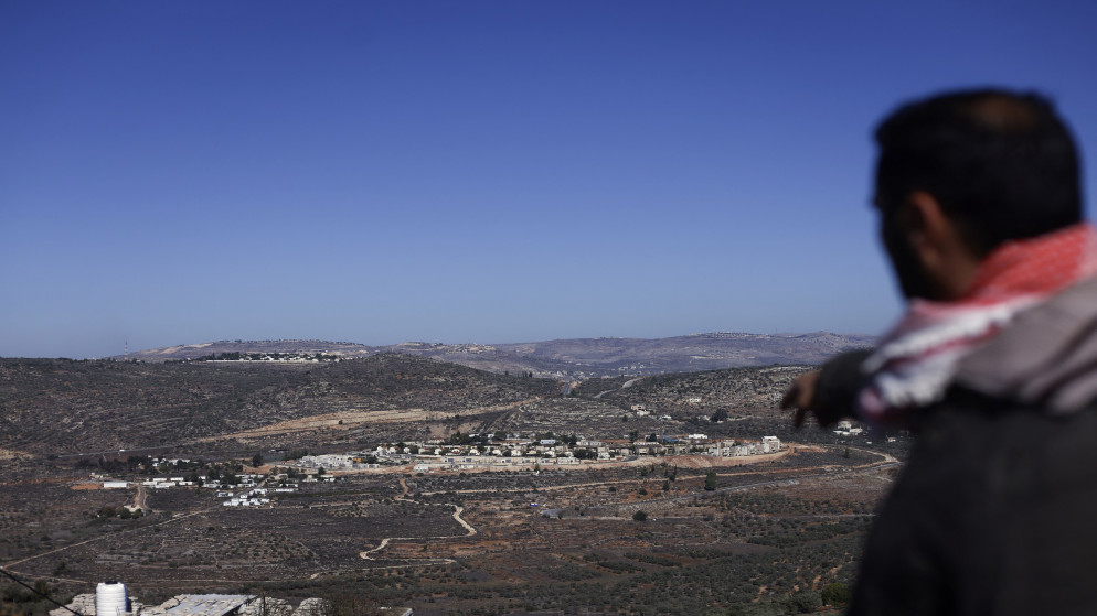 فلسطيني يشير إلى مستوطنة إسرائيلية مبنية على أراضٍ فلسطينية في الضفة الغربية المحتلة. (أ ف ب)