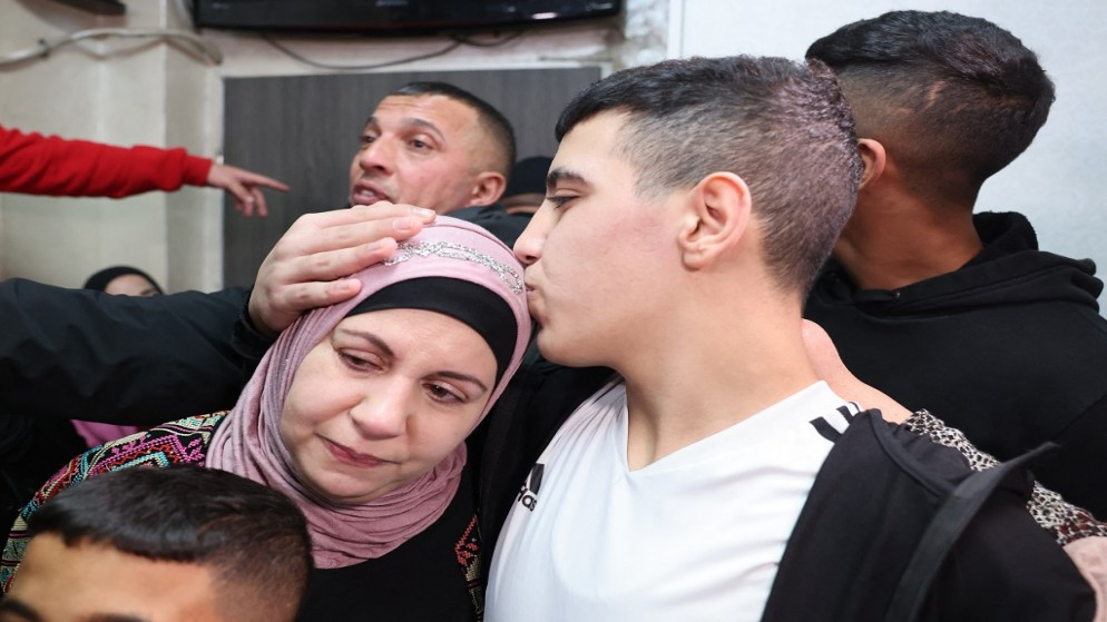 الطفل أحمد سلايمة من القدس المحتلة، يقبل رأس والدته عقب الإفراج عنه من سجون الاحتلال الإسرائيلي (أ ف ب).