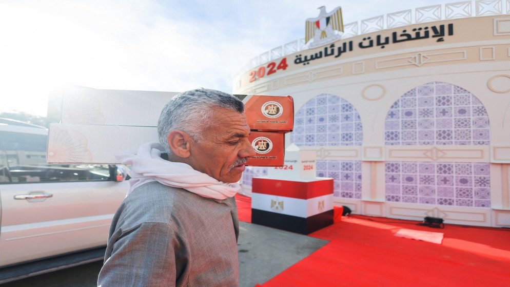 عامل مصري يحمل صندوقا يحتوي مواد التصويت إلى مركز اقتراع في اليوم الأول للانتخابات الرئاسية في القاهرة. 10/12/2023. (رويترز)