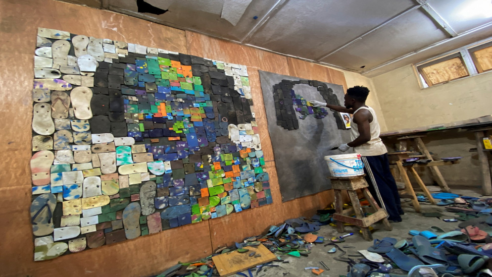 يحول الفنان النيجيري يوجين كومبوي نعالا بلاستيكية تخلص منها أصحابها إلى لوحات ملونة. (رويترز)