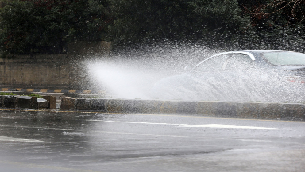 سيارة ترشق مياه أمطار في شارع رئيسي في العاصمة عمّان خلال جو ماطر. (صلاح ملكاوي /المملكة)