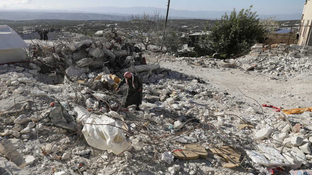 شخص يقف بجانب مبنى منهار بعد زلزال ضرب تركيا وسوريا. (رويترز)