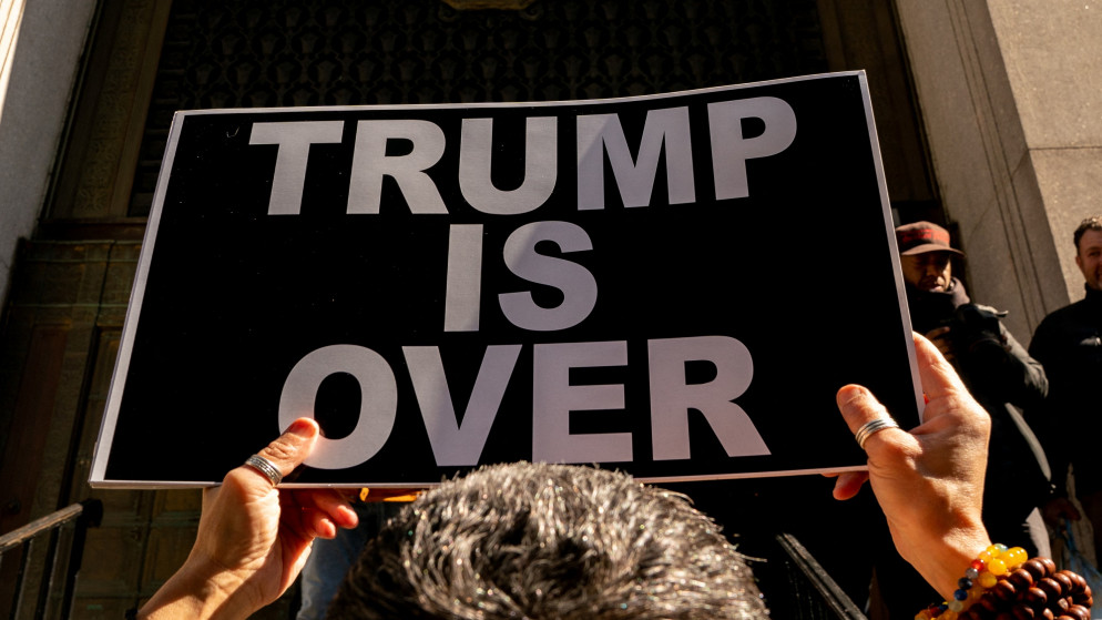 متظاهر يحمل لافتة مكتوب عليها "ترامب انتهى" في نيويورك، 20 آذار 2023. (رويترز)