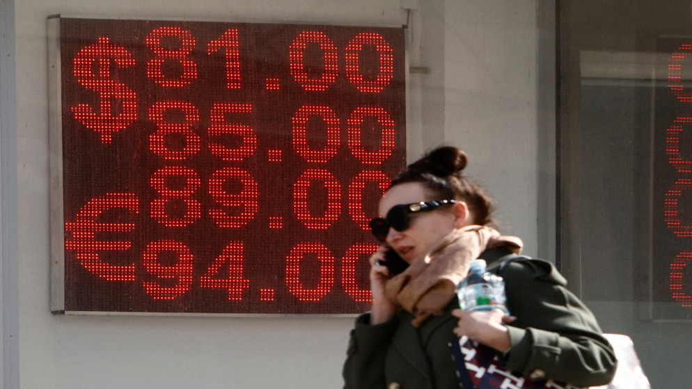 امرأة تسير أمام لوحة تظهر أسعار صرف عملات كالدولار الأميركي مقابل الروبل الروسي في موسكو. (رويترز)