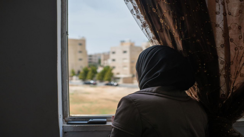 لاجئة سورية تنظر من نافذة المنزل. (محمد حواري/ الأمم المتحدة)