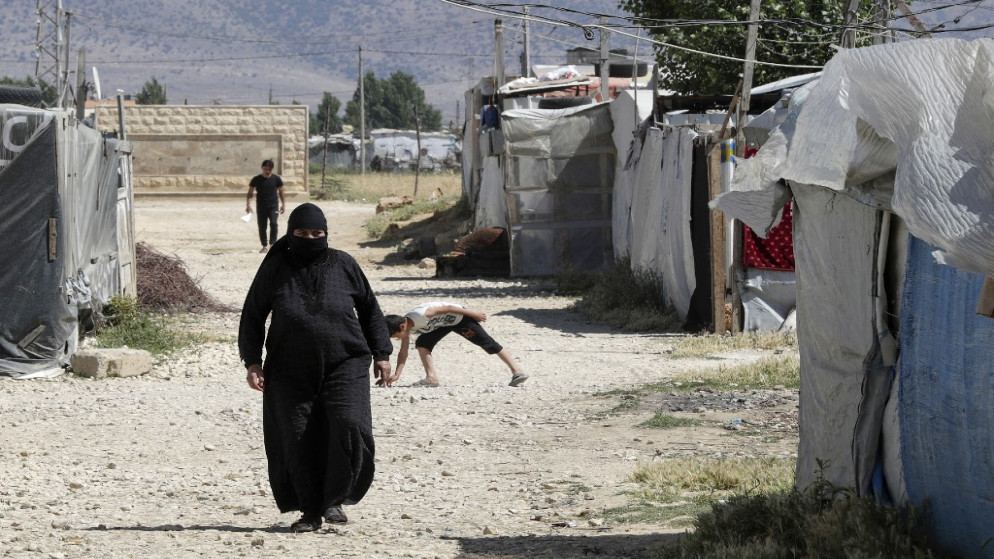امرأة سورية تمشي بين خيام في مخيم للاجئين في سعدنايل في سهل البقاع شرقي لبنان، 13 حزيران 2023. (أ ف ب)