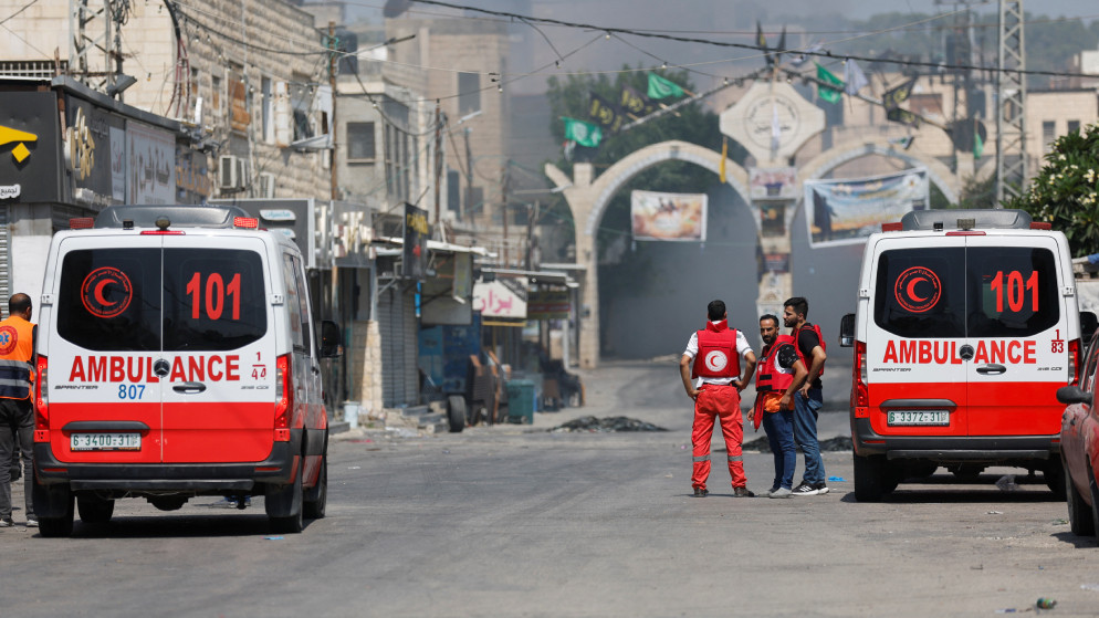 مسعفون فلسطينيون يقفون بينما يتصاعد الدخان خلال اقتحام إسرائيلي لمخيم جنين. 3 تموز 2023. (رويترز)