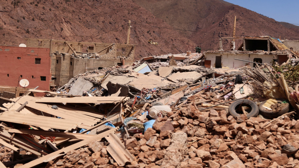 أشخاص يقفون على أنقاض منازل مدمرة في بلدة تلات نيعقوب بفعل زلزال ضرب المغرب. (رويترز)