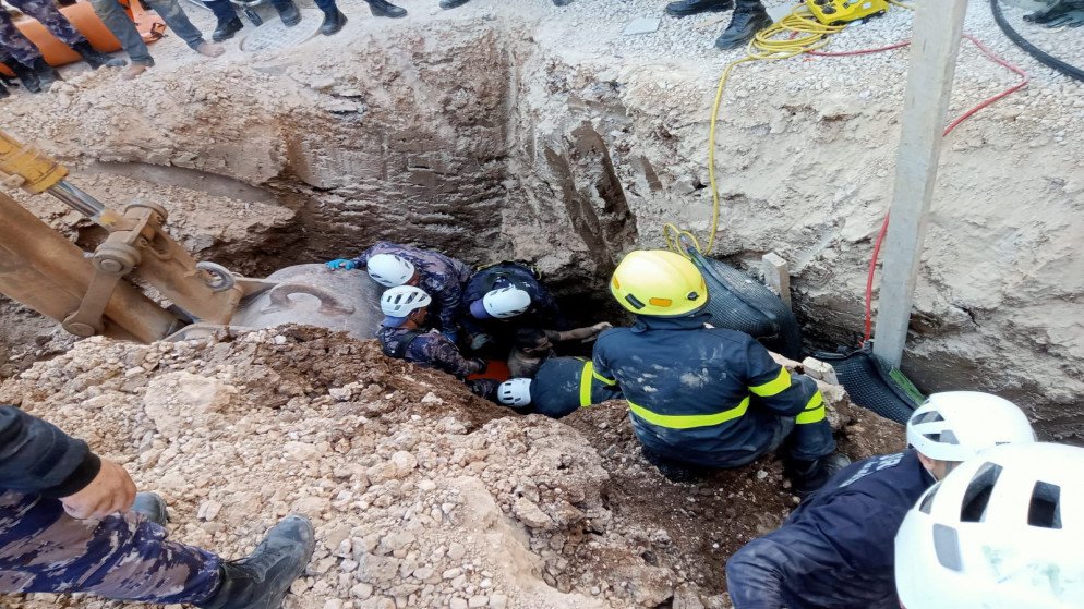 محاولات إخراج شخصين بعد انهيار أتربة على عاملين أثناء قيامهما بحفريات لغايات الصرف الصحي. (مديرية الأمن العام)