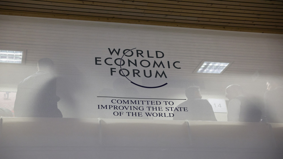 أشخاص يقفون خلف شعار المنتدى الاقتصادي العالمي خلال الاجتماع السنوي الرابع والخمسين في دافوس، سويسرا، في 16 يناير 2024. ( رويترز.)
