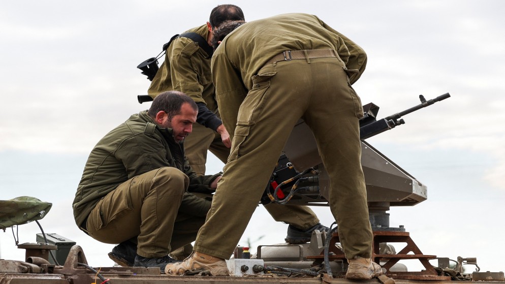 جنود إسرائيليون يتعاملون مع أسلحة على مدرعة إسرائيلية بالقرب من حدود قطاع غزة، 3 كانون الثاني/ يناير 2024. (رويترز)