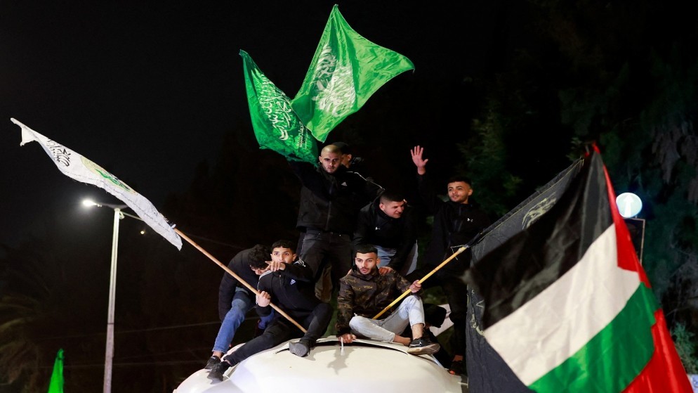 شبان فلسطينيون يلوحون بالأعلام بينما يغادر الأسرى المفرج عنهم سجن عوفر الإسرائيلي في رام الله بالضفة الغربية المحتلة. 26 تشرين الثاني 2023. (رويترز)