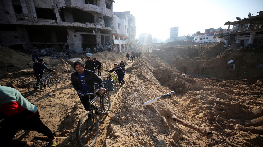 فلسطينيون بجانب مبان مدمرة في مدينة غزة بفعل الضربات الإسرائيلية على القطاع. (رويترز)