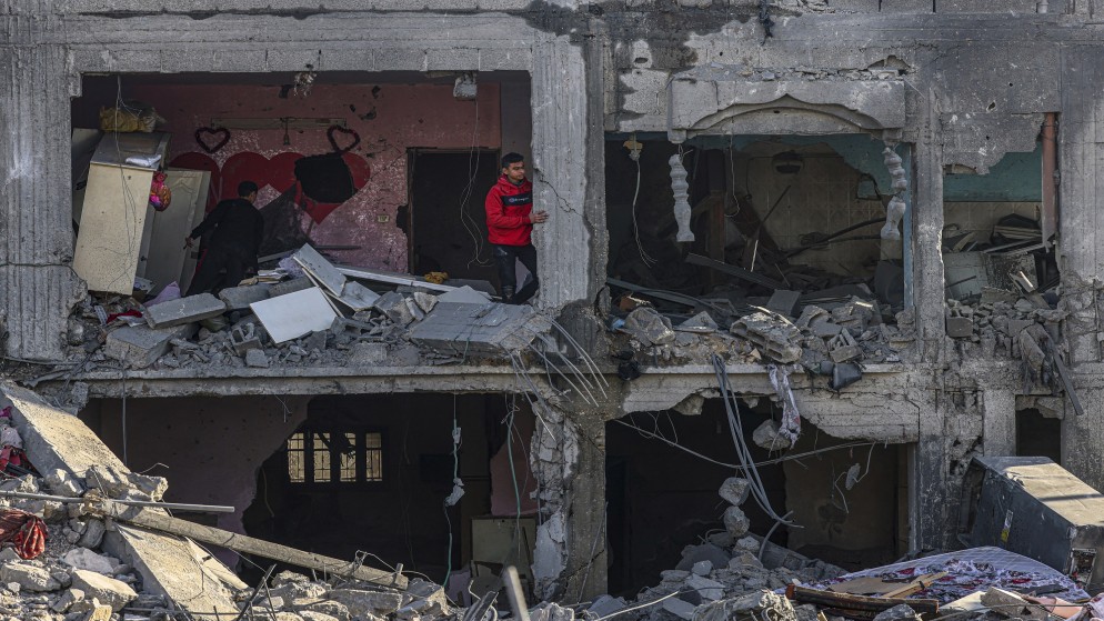 فلسطينيون يتفقدون أضرارا في مبنى دمرته قوات الاحتلال الاسرائيلي في رفح، جنوب قطاع غزة.12 فبراير، 2024،(أ ف ب)