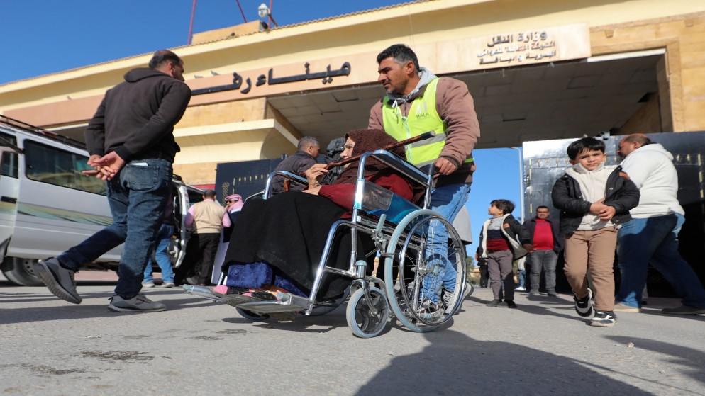 رجل يساعد امرأة فلسطينية مقعدة للخروج من قطاع غزة عبر معبر رفح. (رويترز)