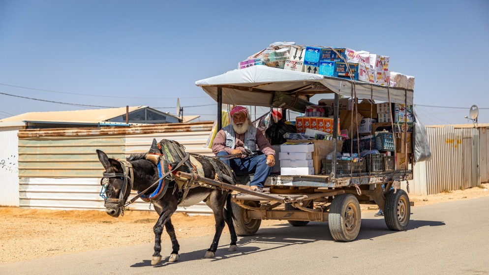 اللاجئ السوري خالد محمد يعمل على عربة يجرها حمار لتوزيع البضائع في مخيم الزعتري، صورة أرشيفية. (شوكت الحرفوش/ UNHCR)