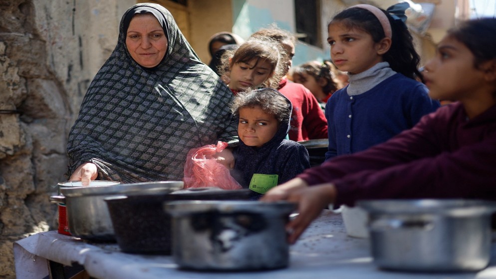 أطفال فلسطينيون ينتظرون الحصول على الطعام المطبوخ في مطبخ خيري وسط نقص الإمدادات الغذائية، في رفح جنوبي قطاع غزة، 5 مارس 2024. (رويترز)