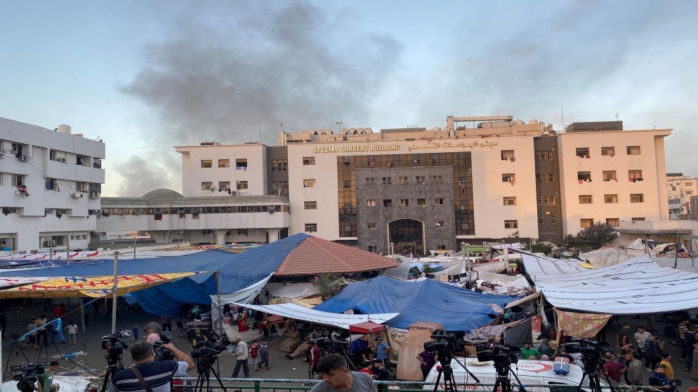 دخان يتصاعد خلف مجمع الشفاء الطبي الذي يضم نازحين بسبب غارات الاحتلال الإسرائيلي على قطاع غزة المحاصر. (رويترز)