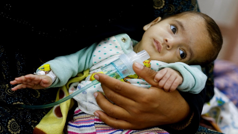 امرأة فلسطينية تحمل ابنتها، في مركز العودة الصحي في رفح جنوبي قطاع غزة، 12 مارس 2024. (رويترز)