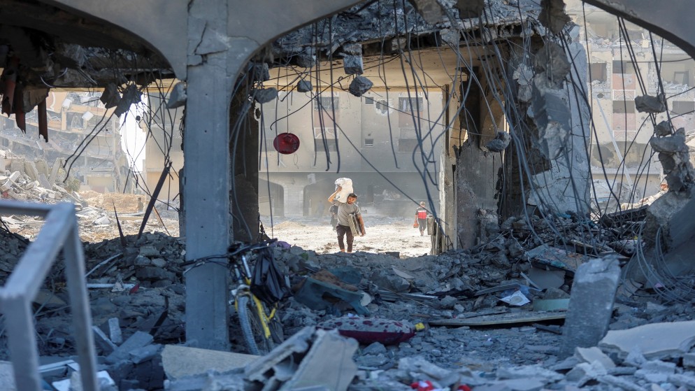 فلسطيني يحمل ممتلكاته ويسير بين أنقاض مبنى سكني مدمر بعد غارة إسرائيلية على مدينة حمد في خان يونس في قطاع غزة. (رويترز)