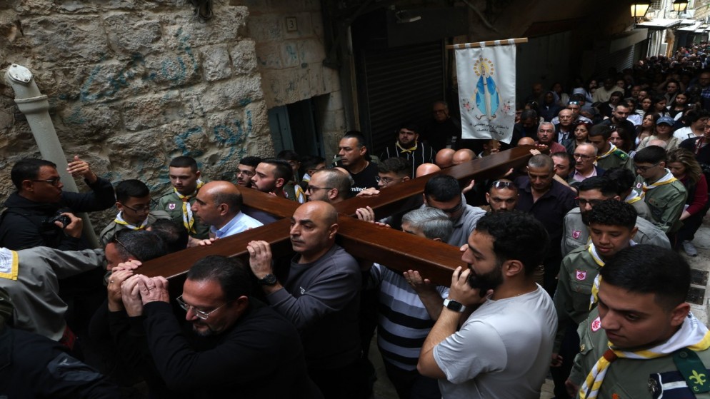 مصلون يحملون صليبًا خشبيًا وهم في طريقهم إلى كنيسة القيامة خلال موكب درب الآلام في البلدة القديمة في القدس المحتلة، 29 آذار/مارس 2024. (أ ف ب)