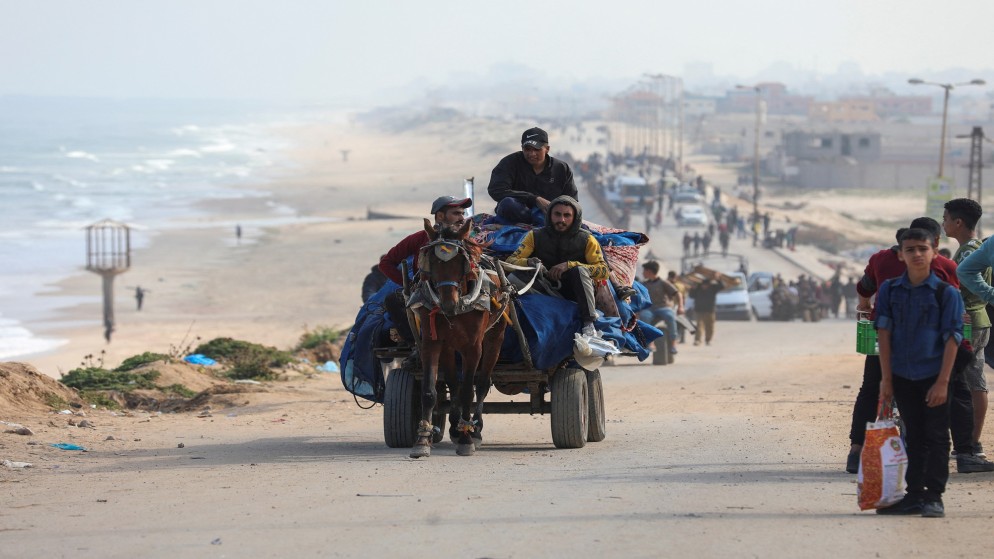 فلسطينيون يركبون عربة يجرها حصان بينما يشق آخرون طريقهم برحلة نزوح بسبب الهجوم العسكري الإسرائيلي على جنوب غزة.15 نيسان/ أبريل 2024. (رويترز)