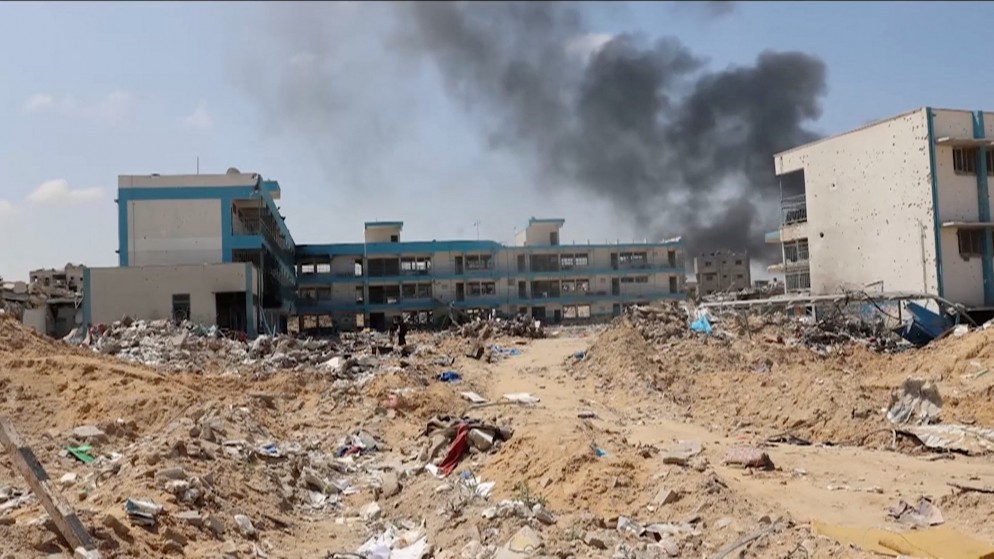 صورة سابقة لتصاعد دخان خلف مبان مدمرة لوكالة "أونروا" في خان يونس جنوبي قطاع غزة. (رويترز)