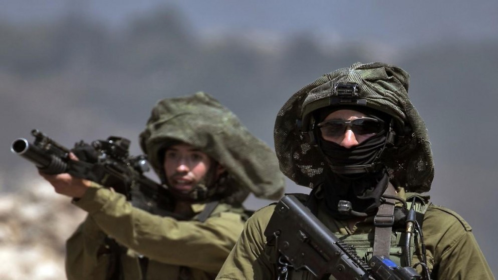 جندي إسرائيلي يوجه بندقيته خلال اشتباكات مع فلسطينيين في الضفة الغربية المحتلة. (أ ف ب)