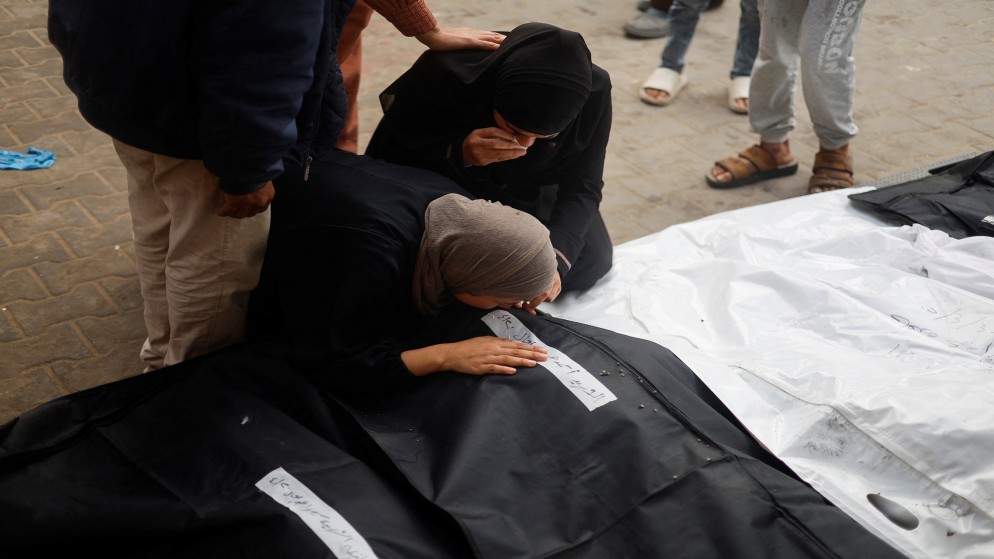 فلسطينيات يبكين بجانب جثامين أقرباء لهن استشهدوا جراء غارات للاحتلال الإسرائيلي في رفح جنوبي قطاع غزة. 21/04/2024. (رويترز)