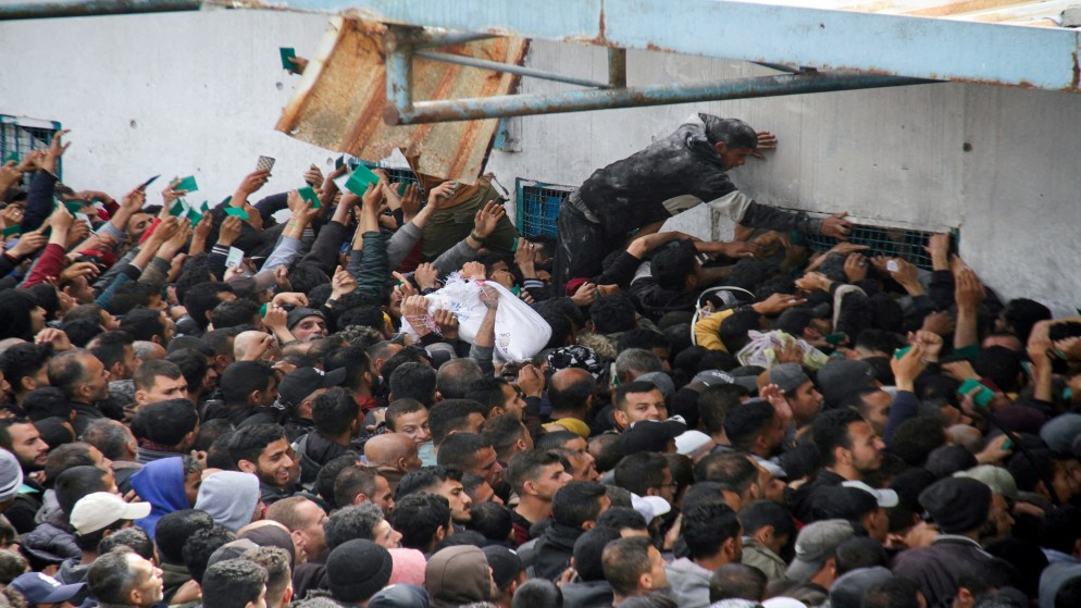 فلسطينيون يتجمعون لتلقي المساعدات خارج مستودع للأونروا في مدينة غزة، 18 آذار/ مارس 2024. (رويترز)