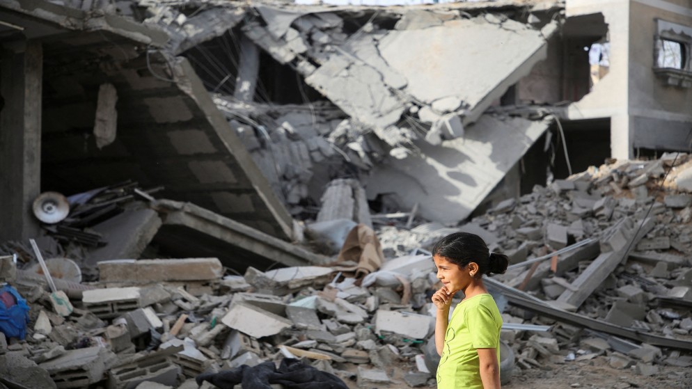 طفلة فلسطينية تسير بجانب مبنى دمرته غارات الاحتلال الإسرائيلي في رفح (رويترز)