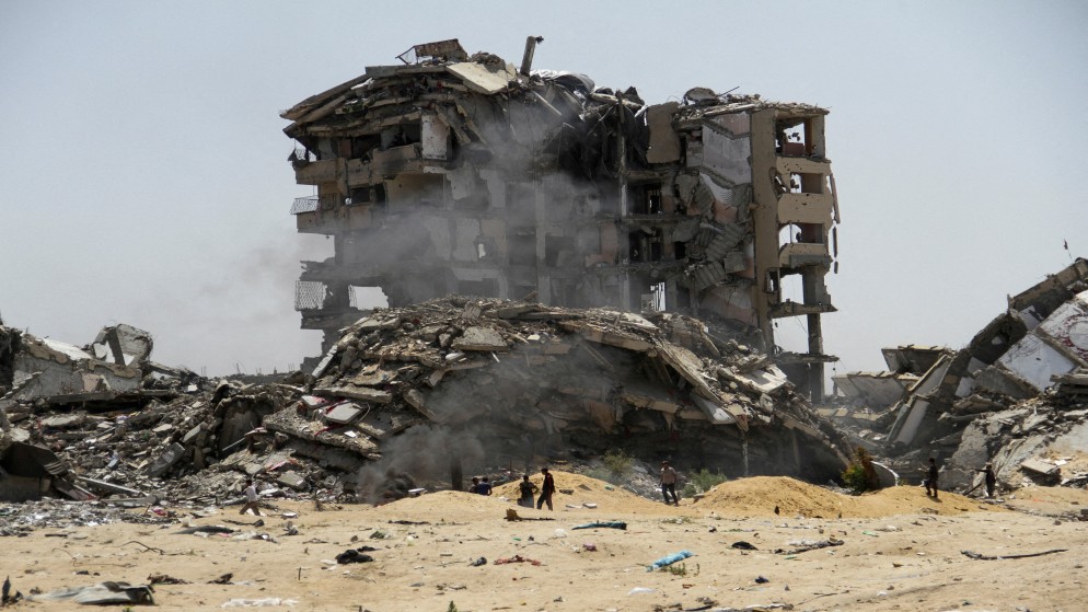 فلسطينيون يسيرون بجوار أنقاض مبان سكنية شمال قطاع غزة دمرتها ضربات الإسرائيلية، 22 نيسان/أبريل 2024. (رويترز)