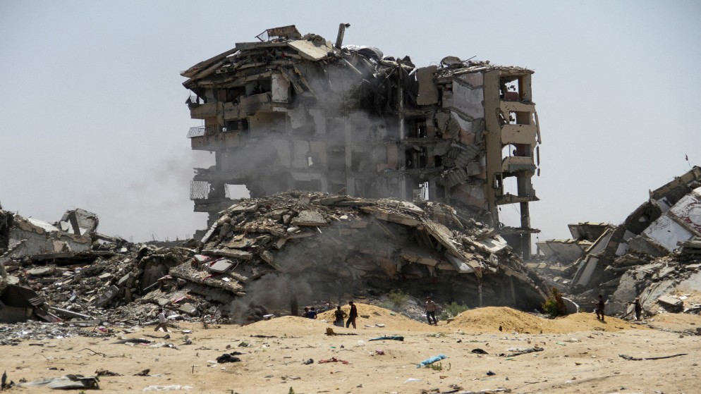 فلسطينيون قرب مبنى مدمر شمال قطاع غزة. (رويترز)